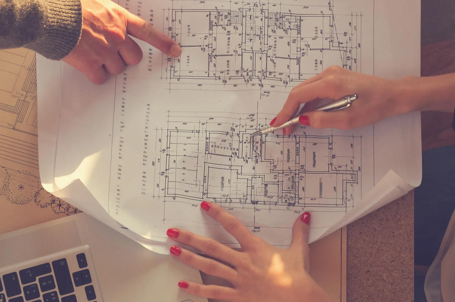 The hands of two people working on a hall plan
